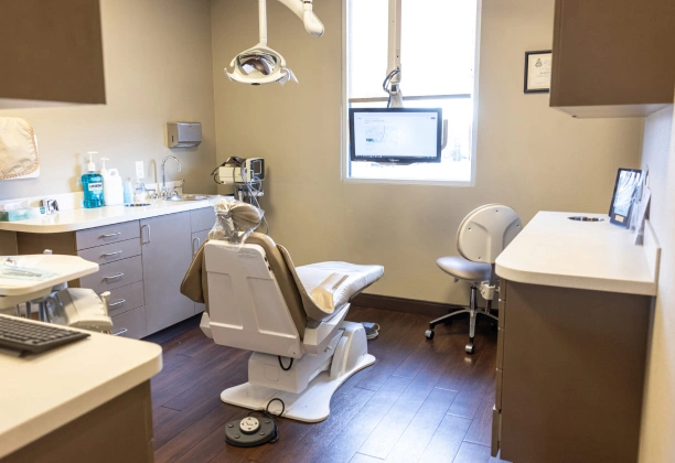 Modern dental operatory with treatment chair, overhead light, and sterilization equipment at Colorado Periodontal Associates.