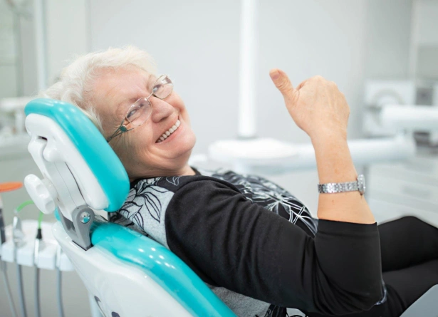 Senior woman smiling in dental chair during checkup at periodontal office.