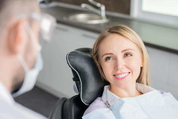 Woman smiling at dental patient in modern dental office treatment room.