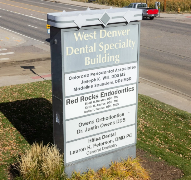 Roadside monument sign for West Denver Dental Specialties Building listing dental practices and doctors.